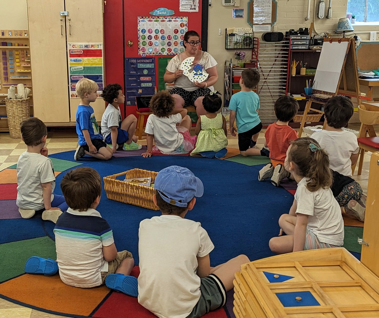 Children in a Sunrise Montessori classroom during circle time with their guide