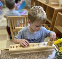 Child concentrating on wooden cylinder math materials