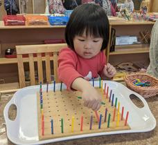 Child working with colourful peg board