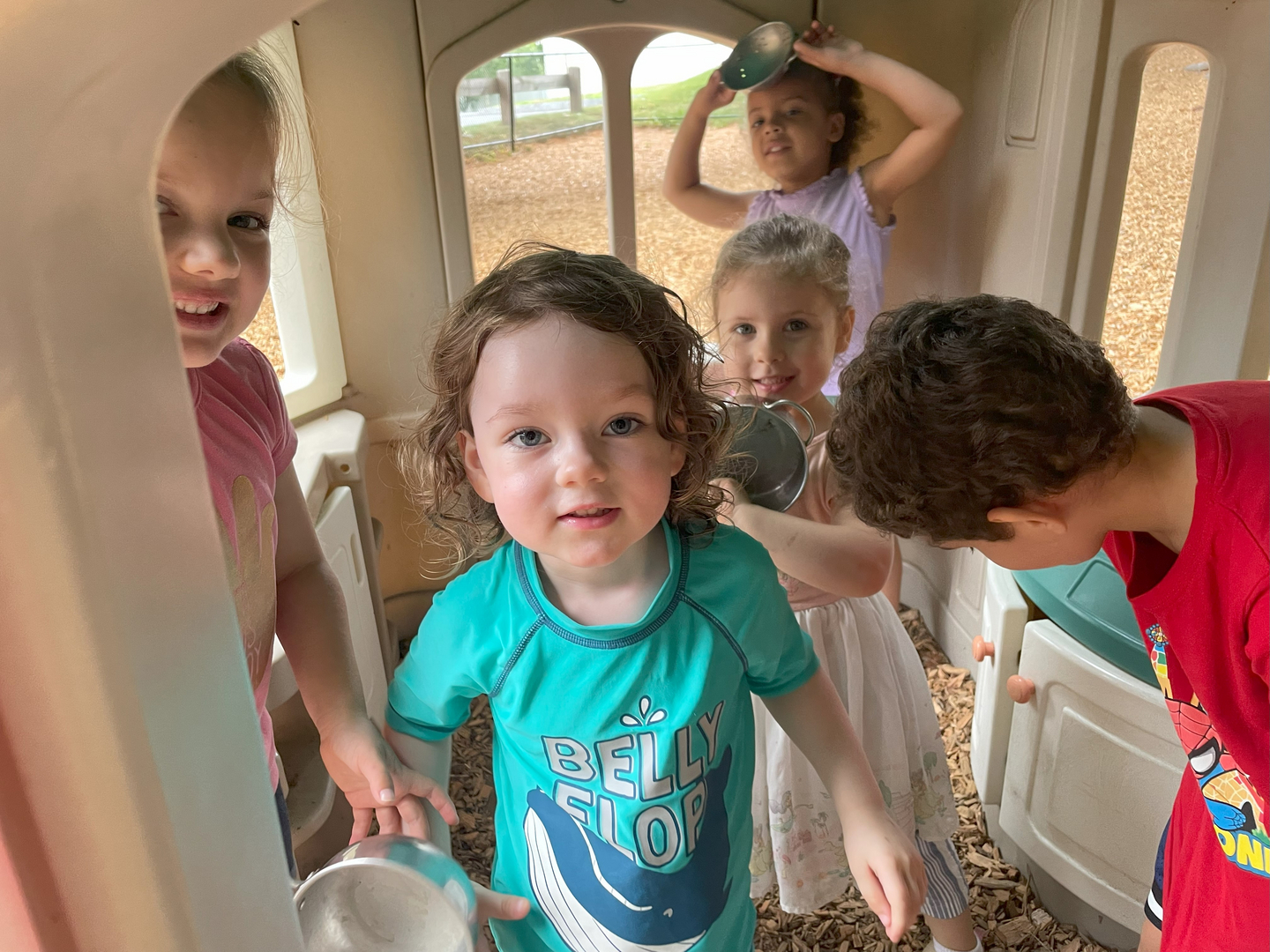 Group of children playing joyfully inside the outdoor playhouse